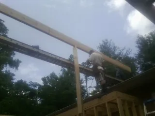 Carpenter setting a ridge beam over a new addition frame — Ice Dam Removal by Roofing Brothers in Ossian