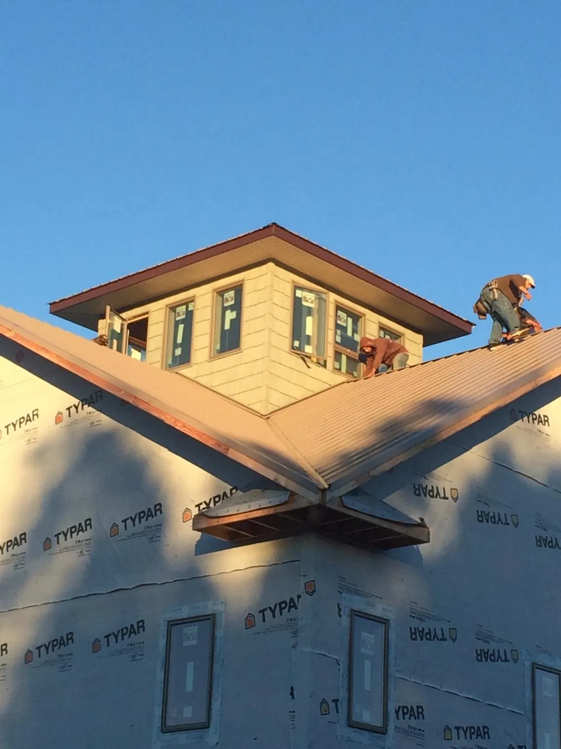 Roofers working around a rooftop cupola on a new metal roof at sunset — Roof Waterproofing in Ossian by Roofing Brothers